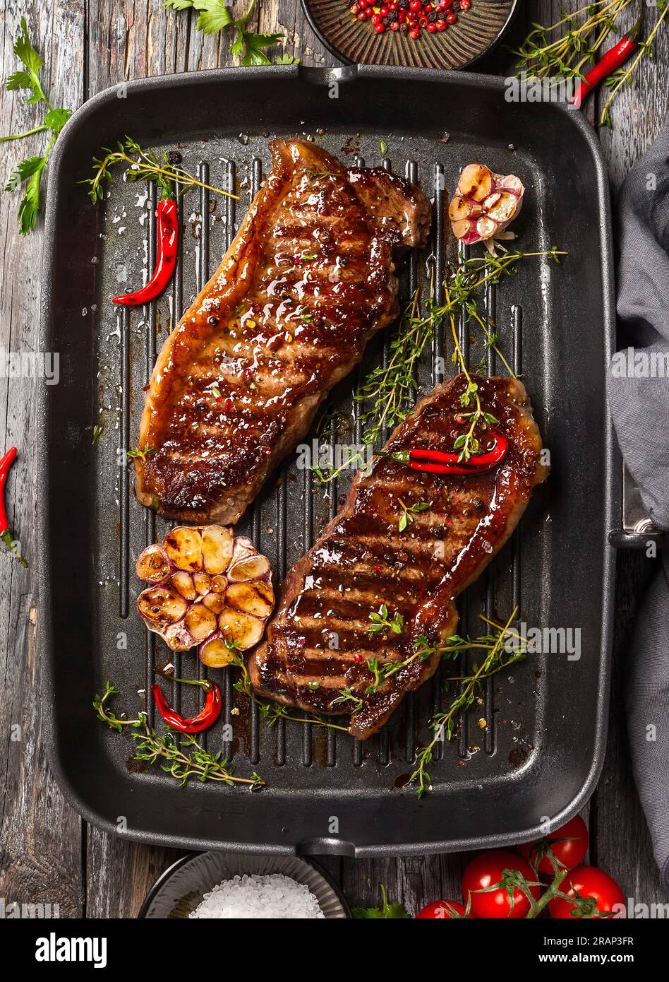Grilled striploin steak with spices and herbs on grill iron pan.The