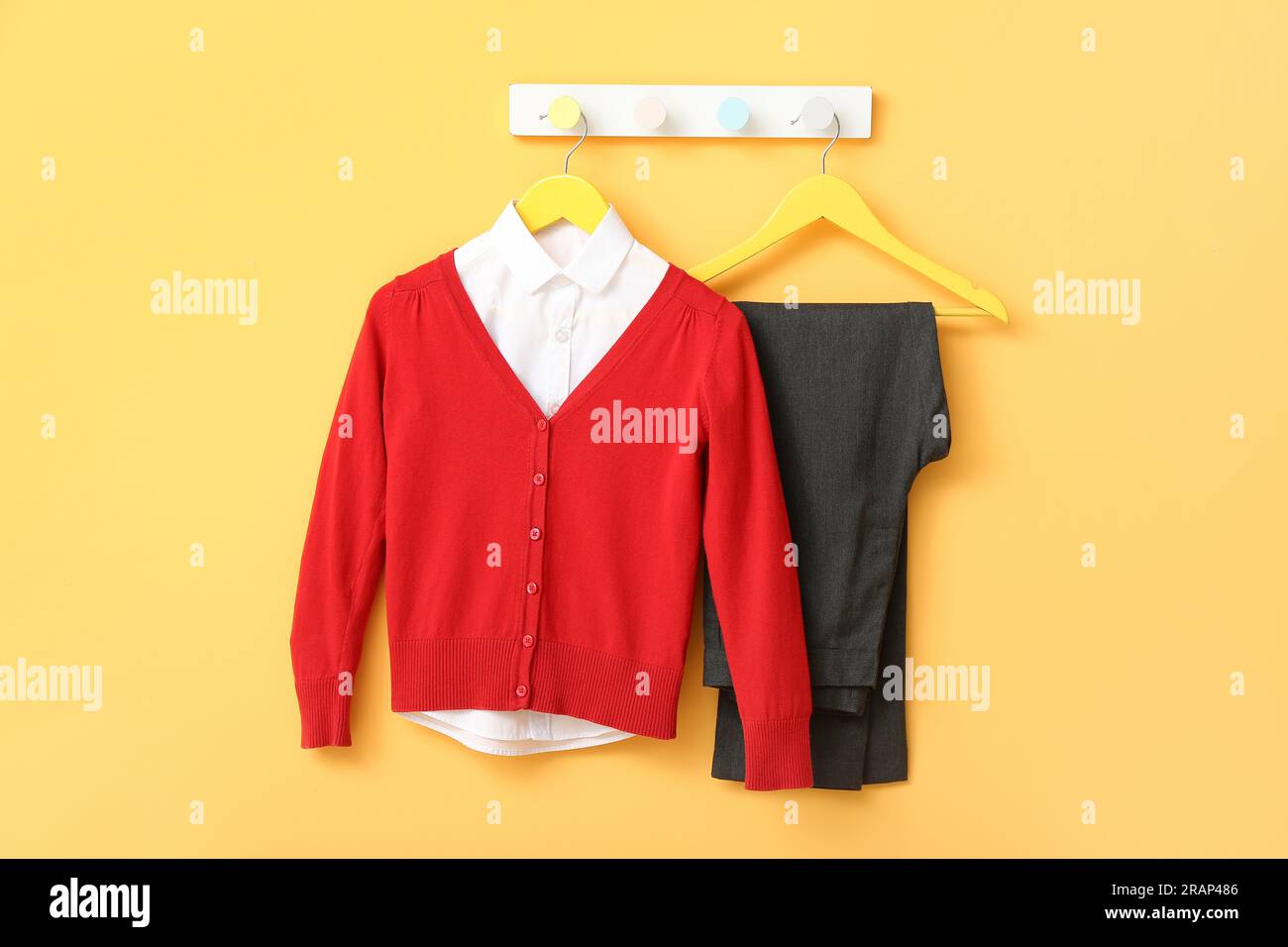 Stylish school uniform hanging on rack against yellow wall Stock Photo ...