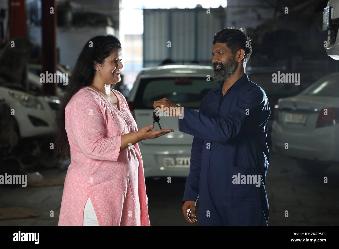 Indian car mechanic delivering the car keys to the happy customers