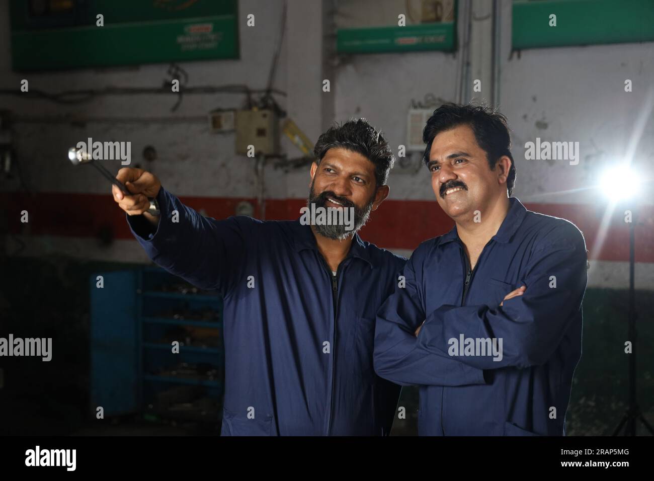 Portrait of happy Indian car mechanics standing together in service station. Car Specialists holding car repairing tools. Professional repairmen Stock Photo