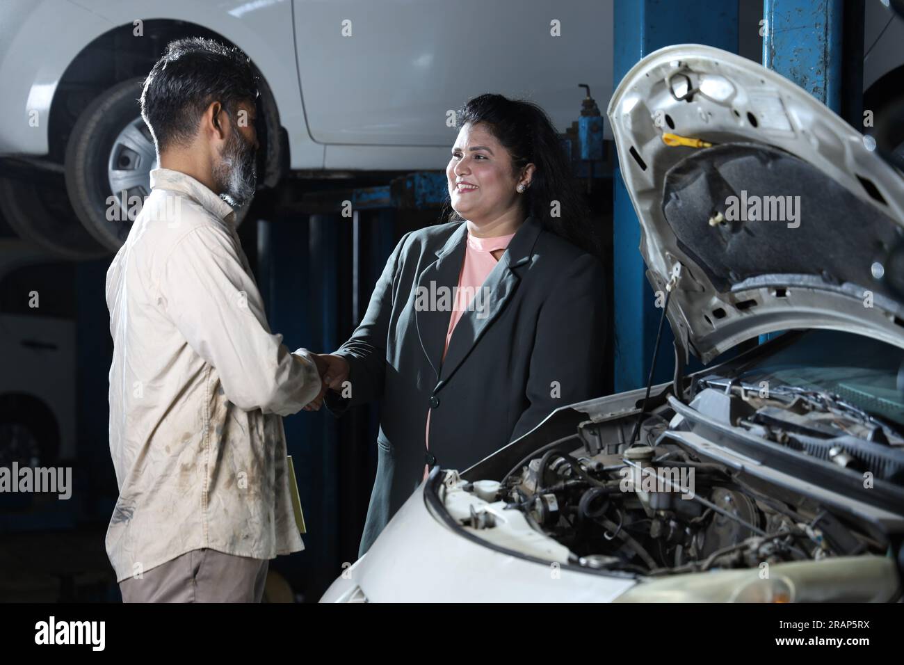 Portraying customer trust and satisfaction towards the service station standing with a car specialist taking brief from the customer Stock Photo