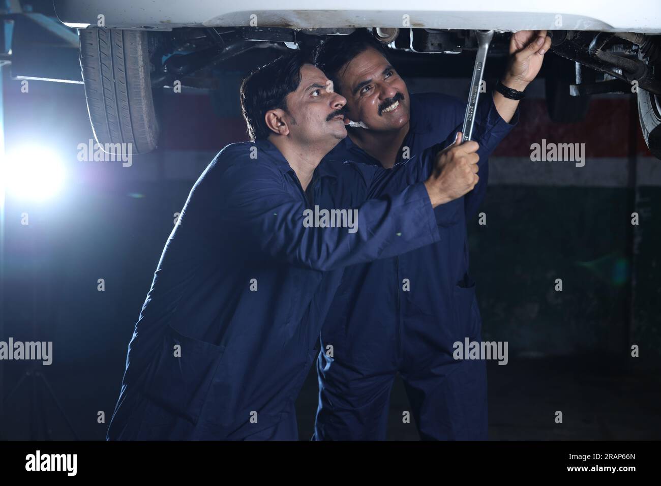 Car specialists examining the lifted car. Professional repairmen