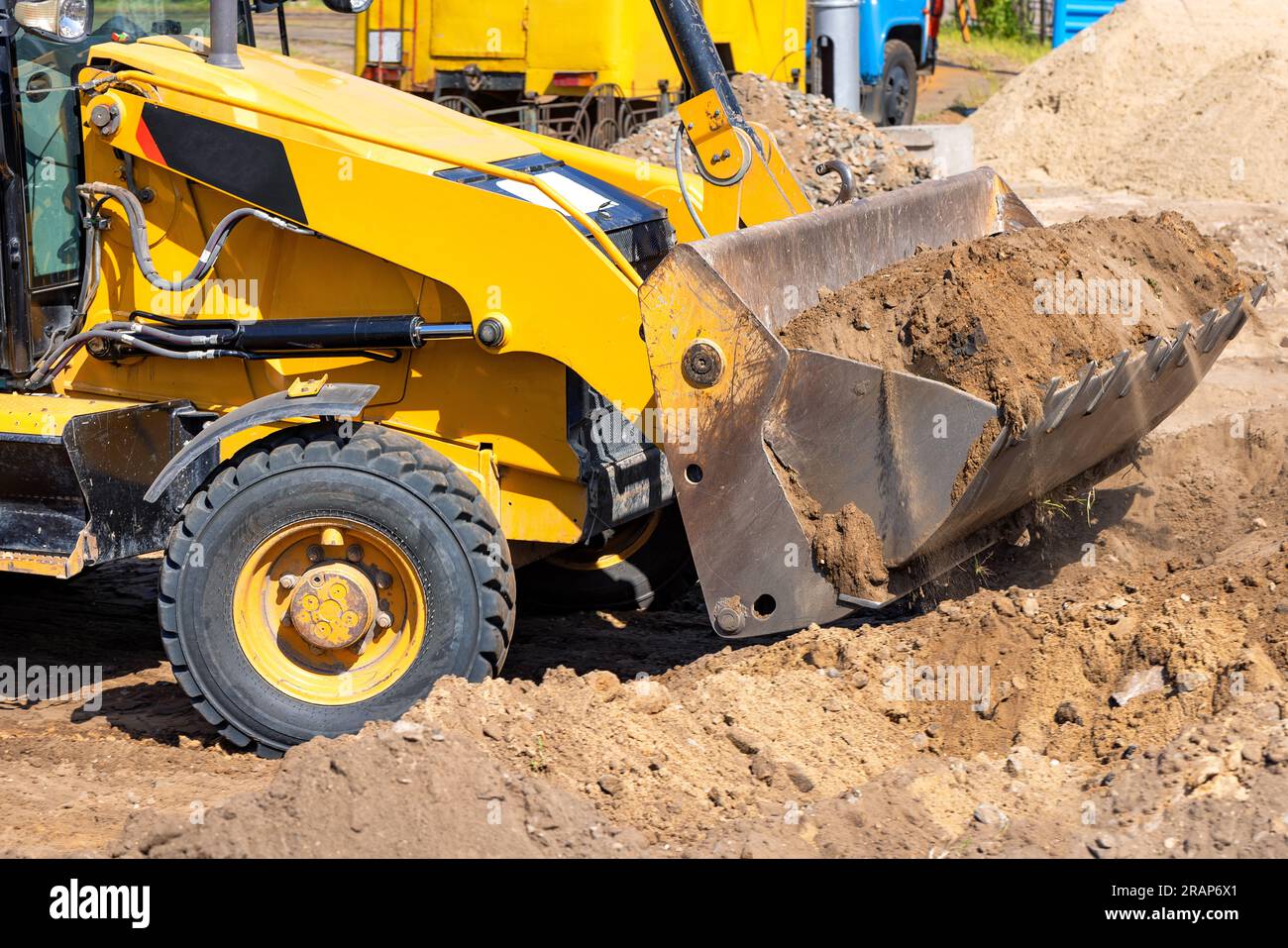 Earthworks are carried out by a wheeled tractor bulldozer using a large metal bucket. Stock Photo
