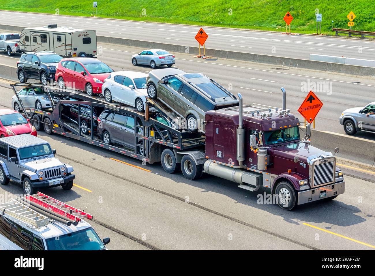 A truck transporting brand-new cars or vehicles on Highway 401 Stock Photo