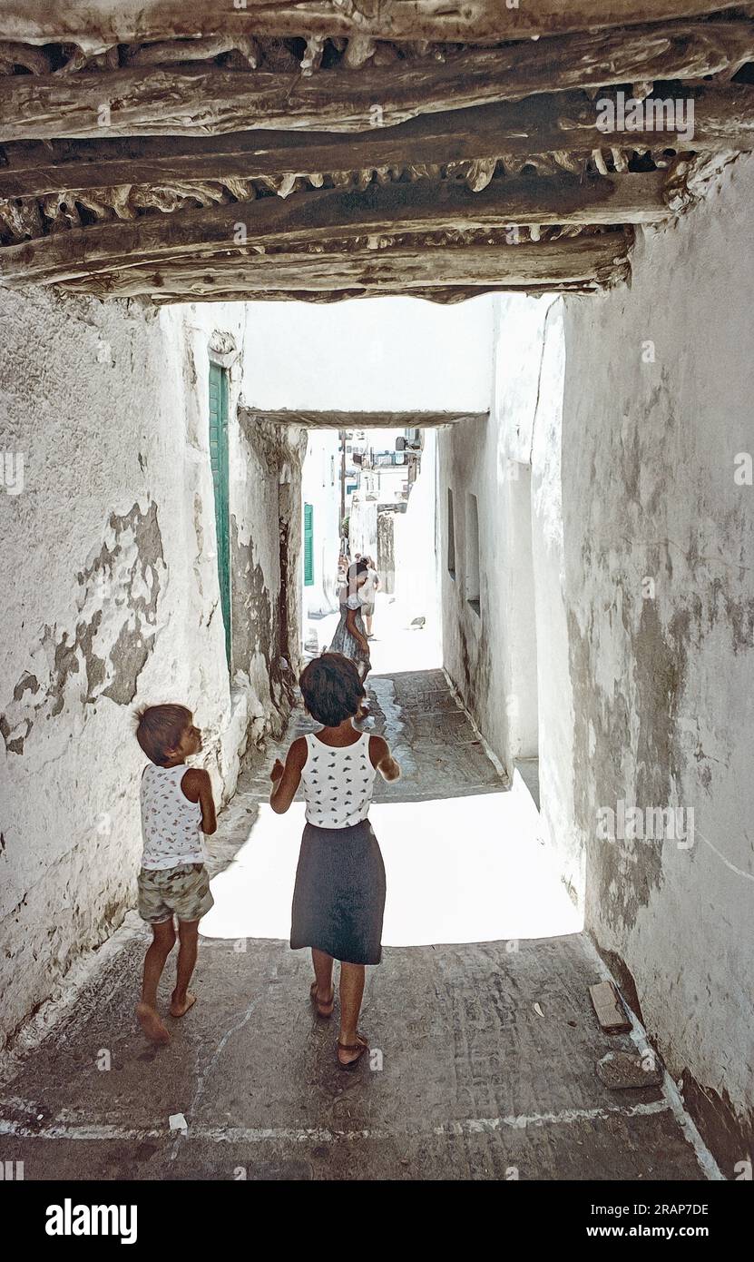 Scanned archival image with photo paint effect of Children in an alley at  at Ios in the Cyclades, Greece 1976. A photo illustration. Stock Photo