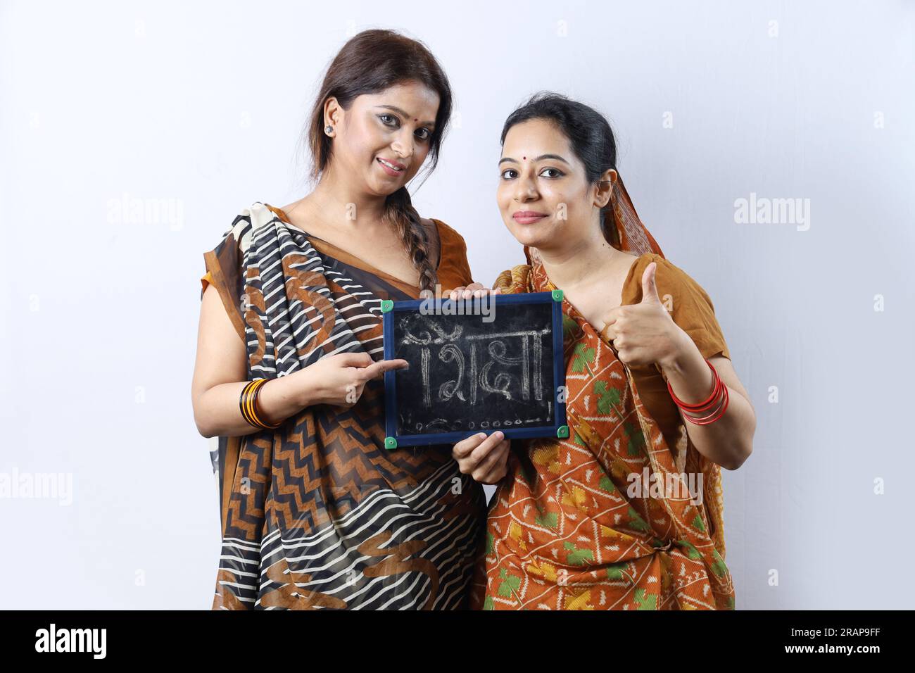 Young rural Indian women holding a writing board in hand. Both wearing ...