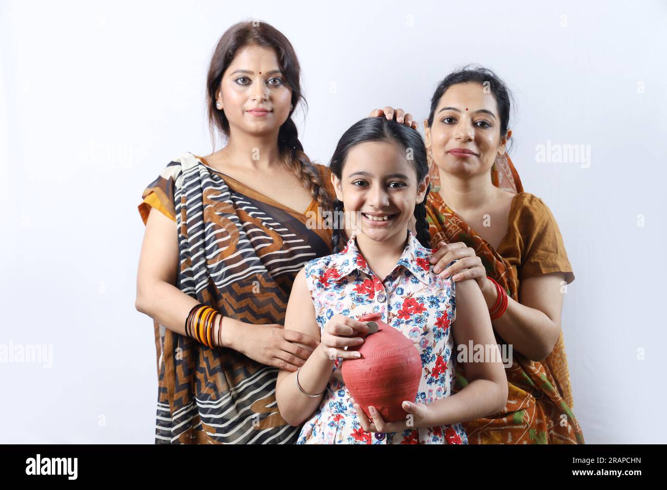 Happy rural Indian villager family of women saving money for future in piggy bank. Aspirational lady showing saving money concept. Stock Photo
