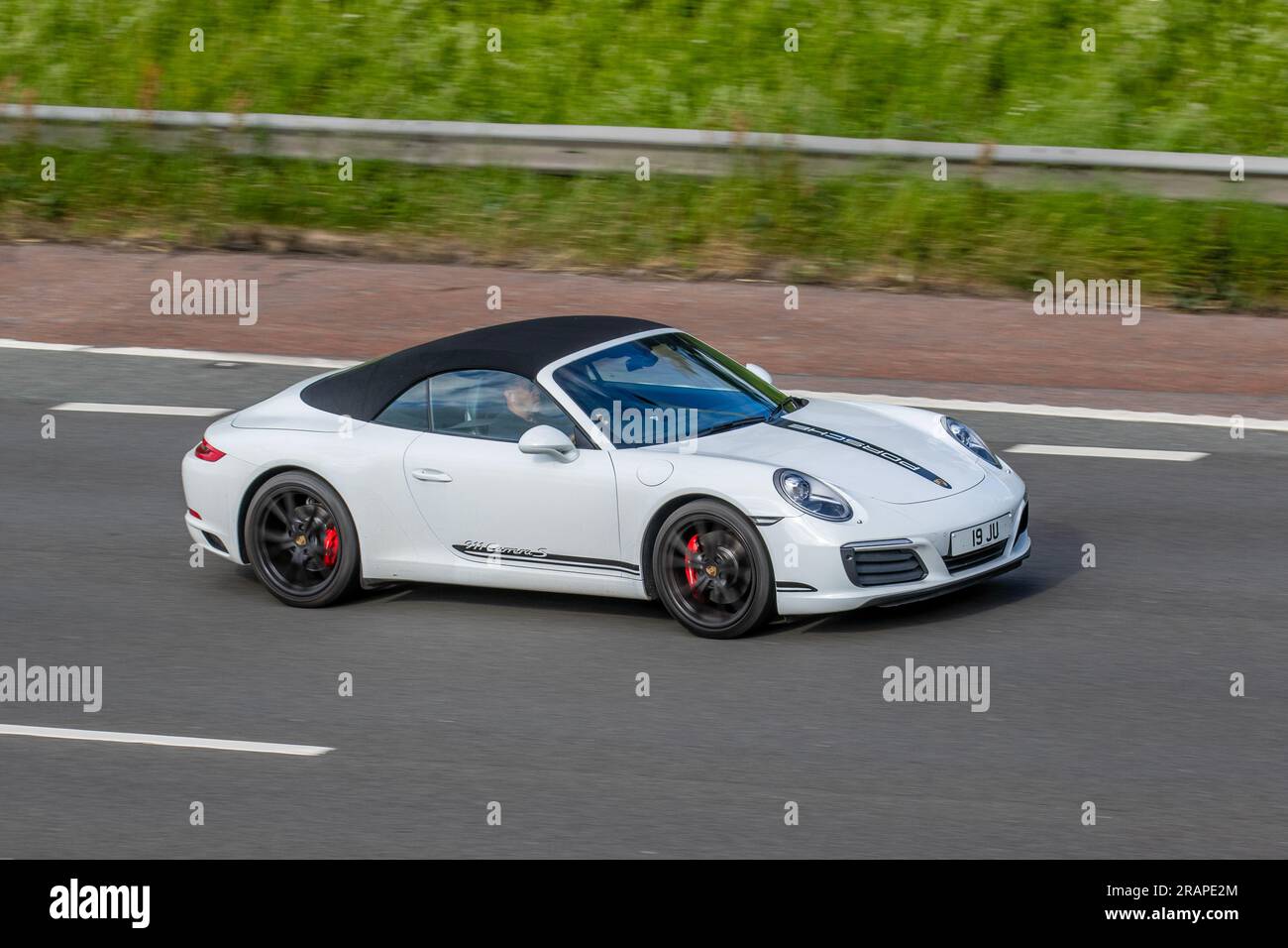 2017 White Porsche 911 Carrera S S-A travelling at speed on the M6 motorway in Greater Manchester, UK Stock Photo