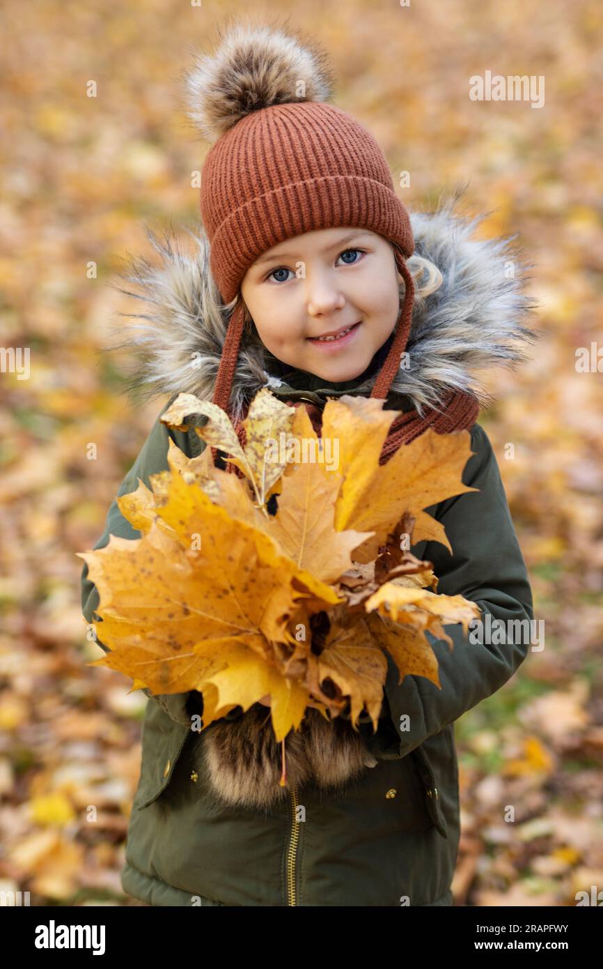 Cute happy little girl in autumn park with maple foliage Stock Photo ...