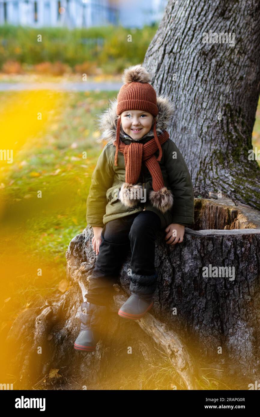 Happy little girl sitting on tree in autumn park Stock Photo - Alamy