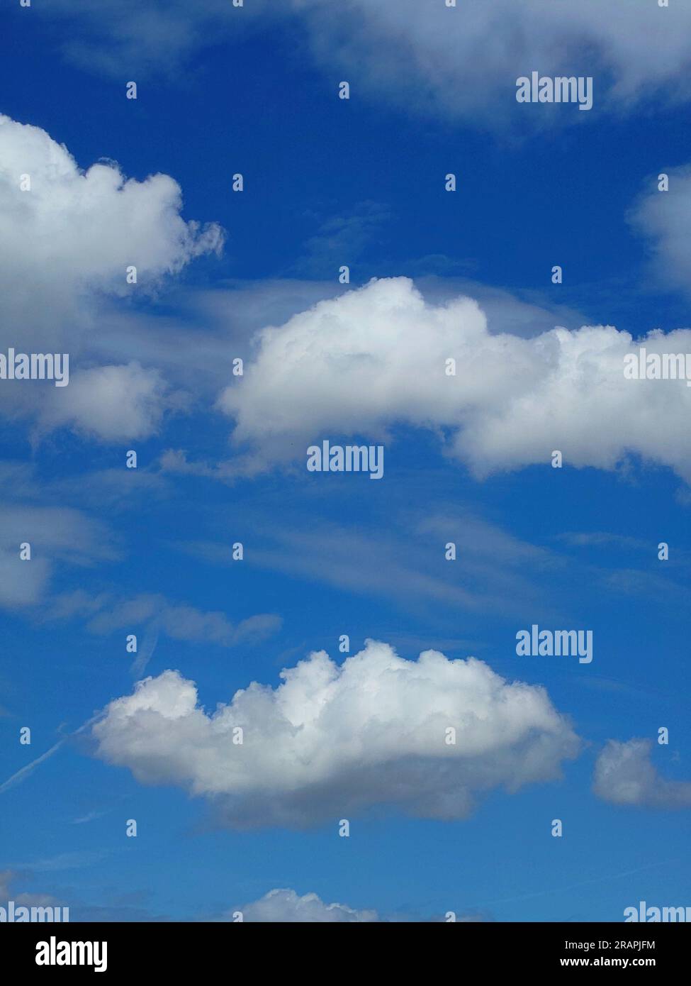 White puffy clouds set against a deep blue summer sky. Stock Photo