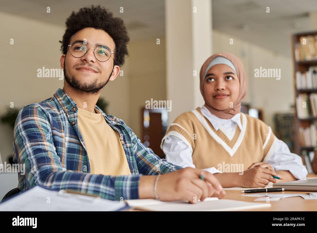 Foreign students studying languages while sitting at table with textbooks in class Stock Photo