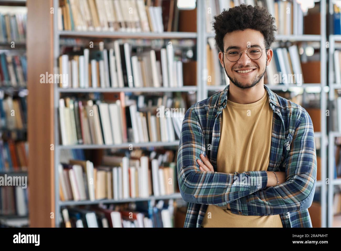 Portrait of adult student standing with his arms crossed and smiling at ...