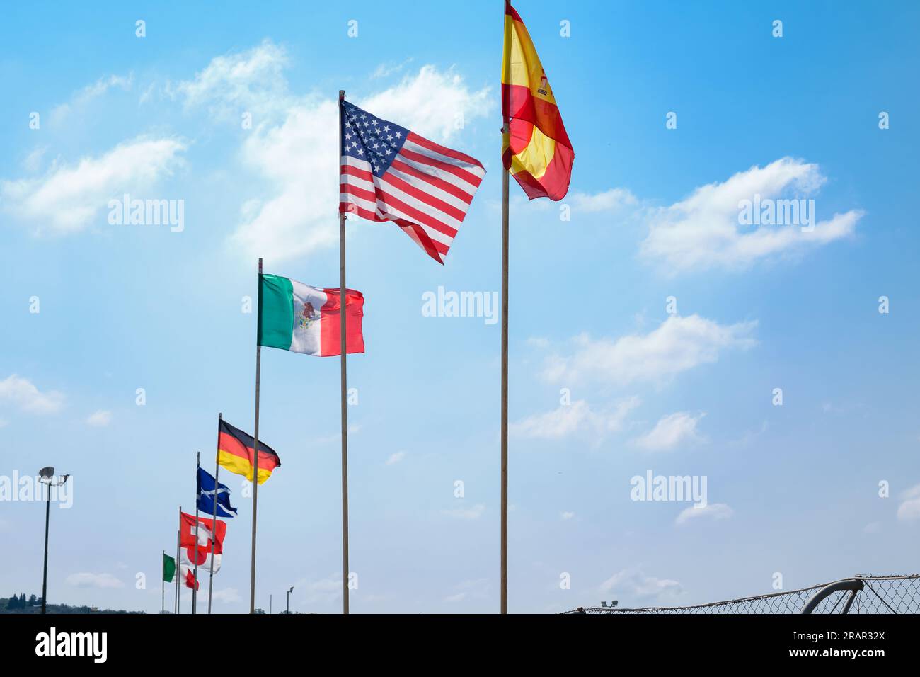 Many flags of different nations aligned waving, clear sky with light white clouds, world conference concept. Stock Photo