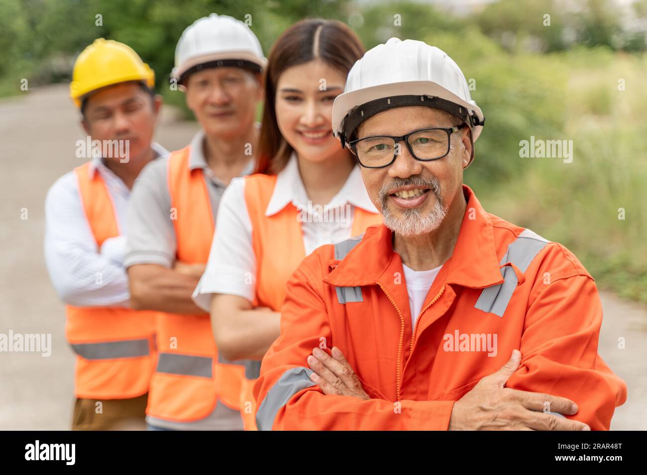 Group of happy 3 males and 1 female engineers wearing orange jumpsuit