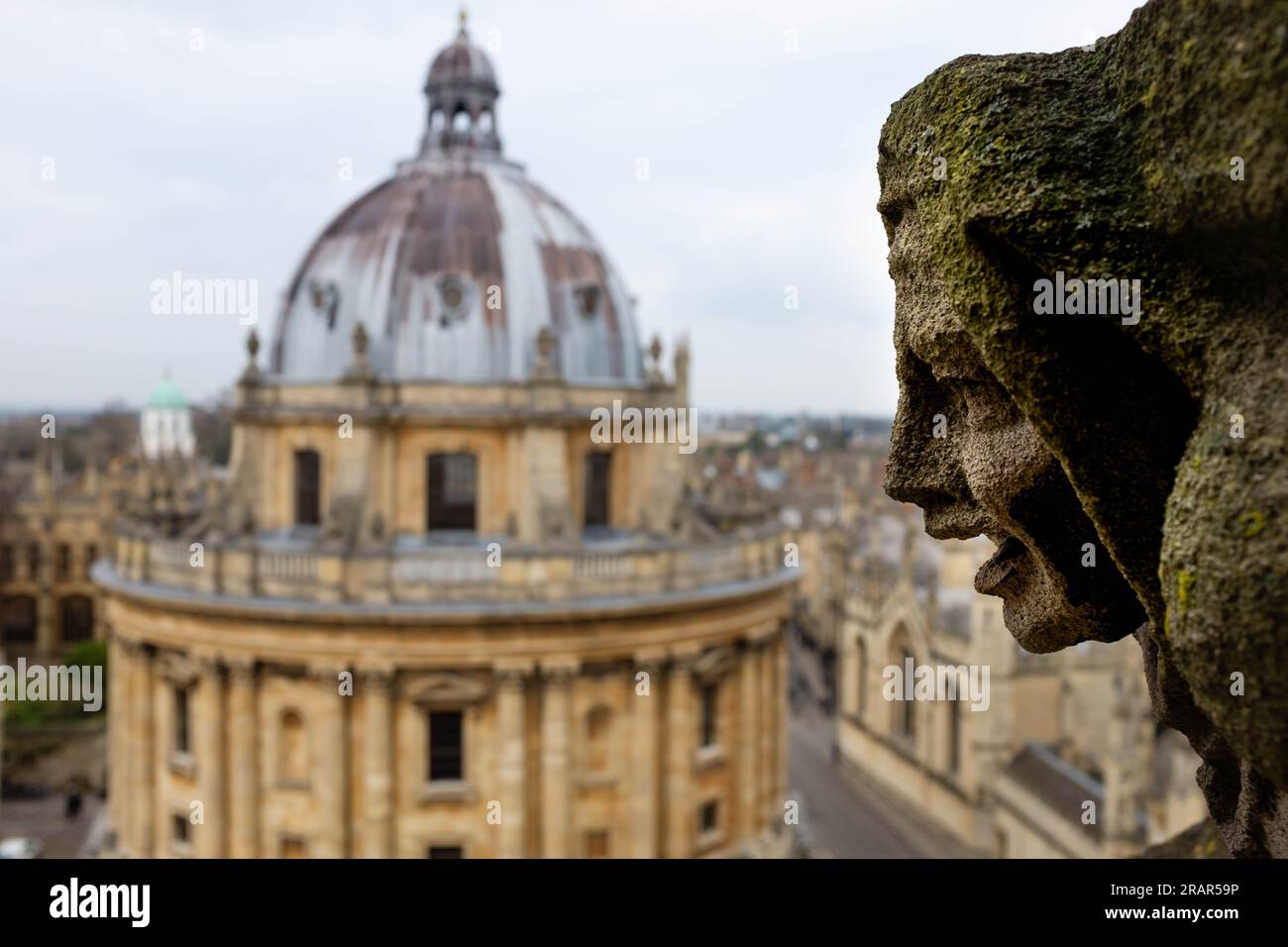 A gargoyle on St. Marys Church, Oxford, looks out over Radcliffe Square towards the Radcliffe Camera Stock Photo
