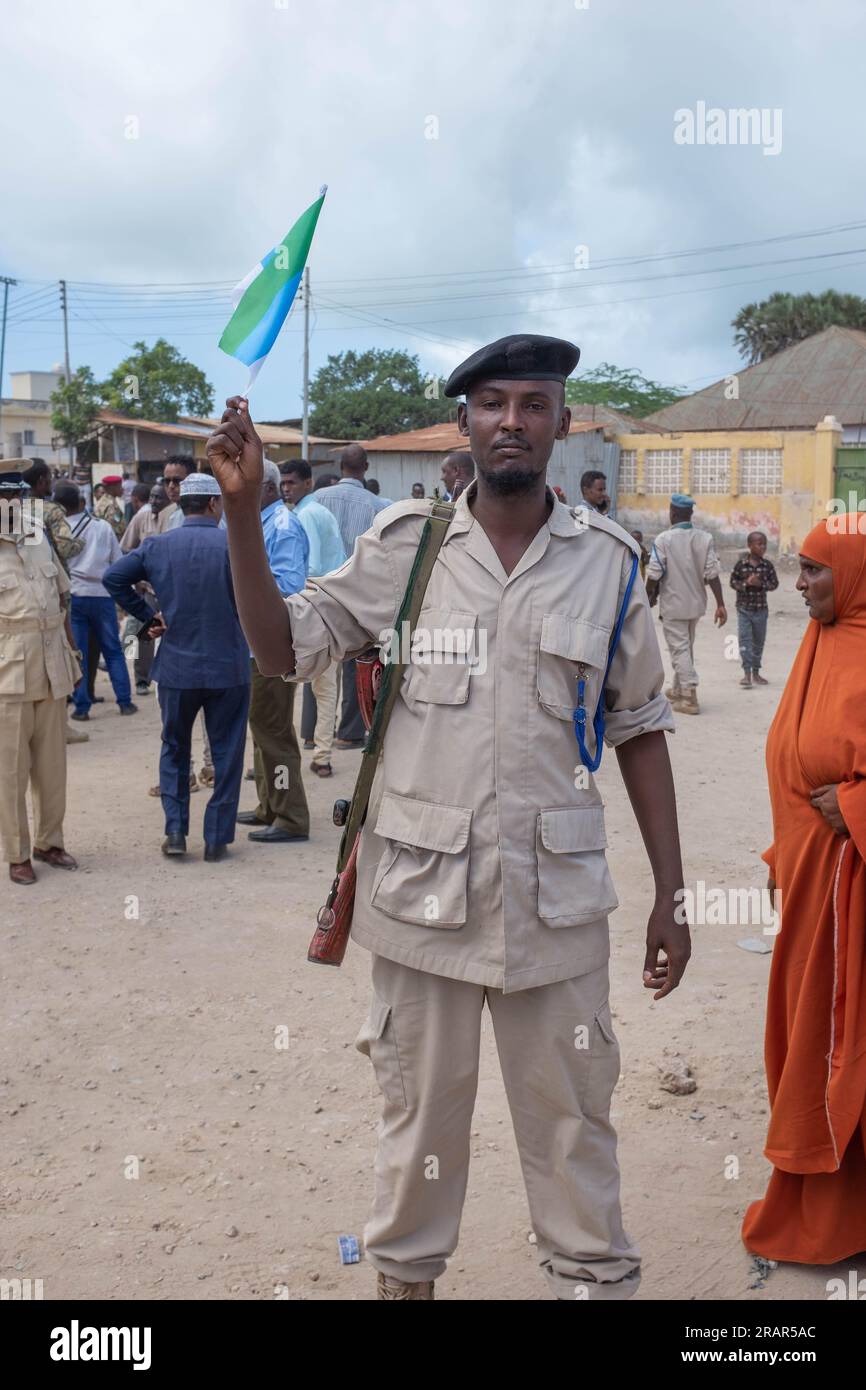 A policeman armed with a rifle waves a flag, Kismayo, Southern Somalia Stock Photo