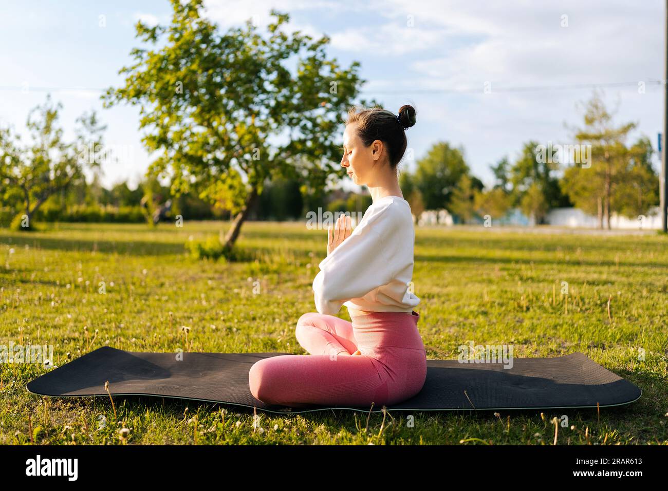 Side view of young serene woman leading a healthy lifestyle, meditating, sitting in lotus