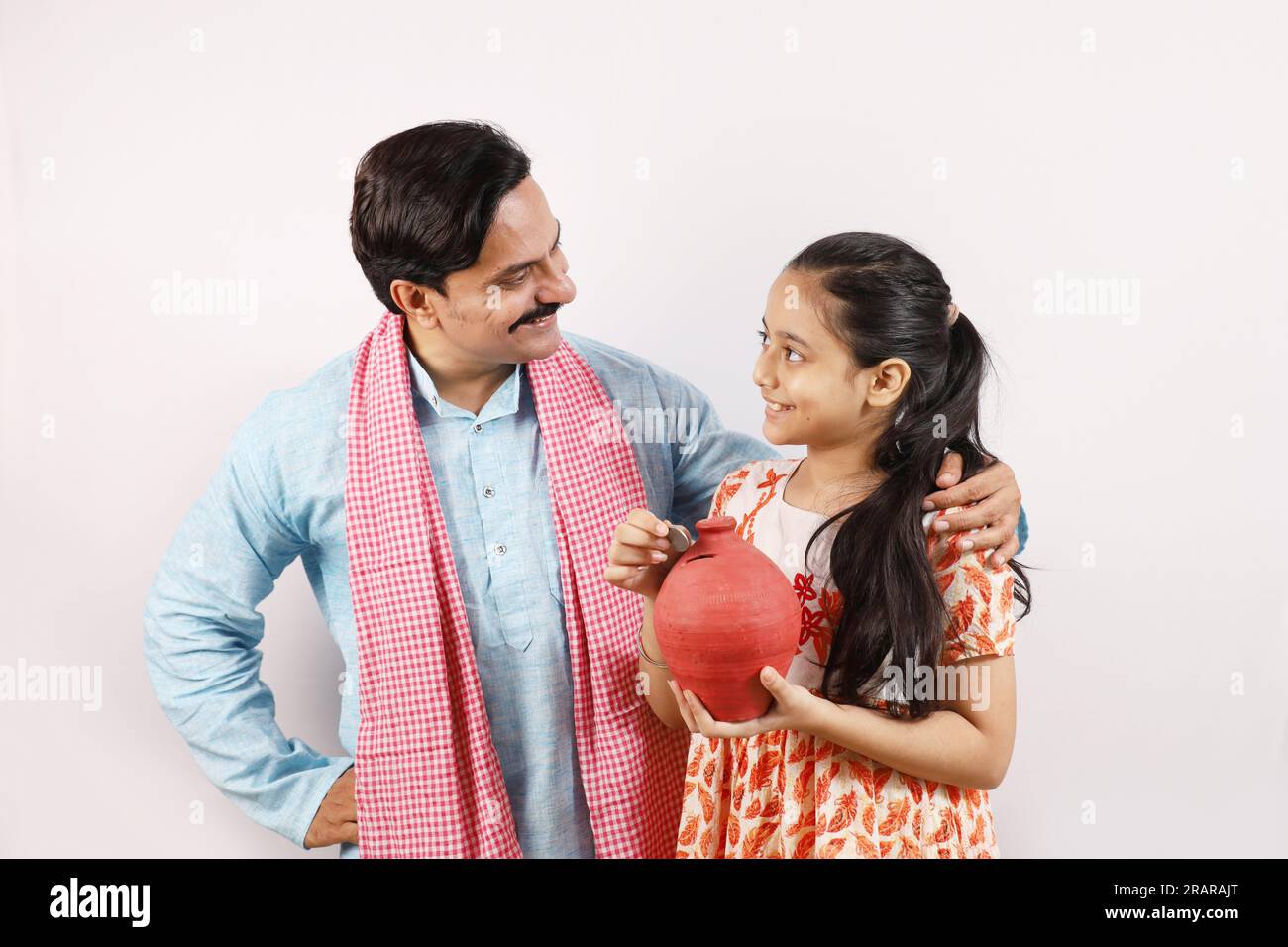 Happy Indian rural father and daughter holding piggy bank in hand ...
