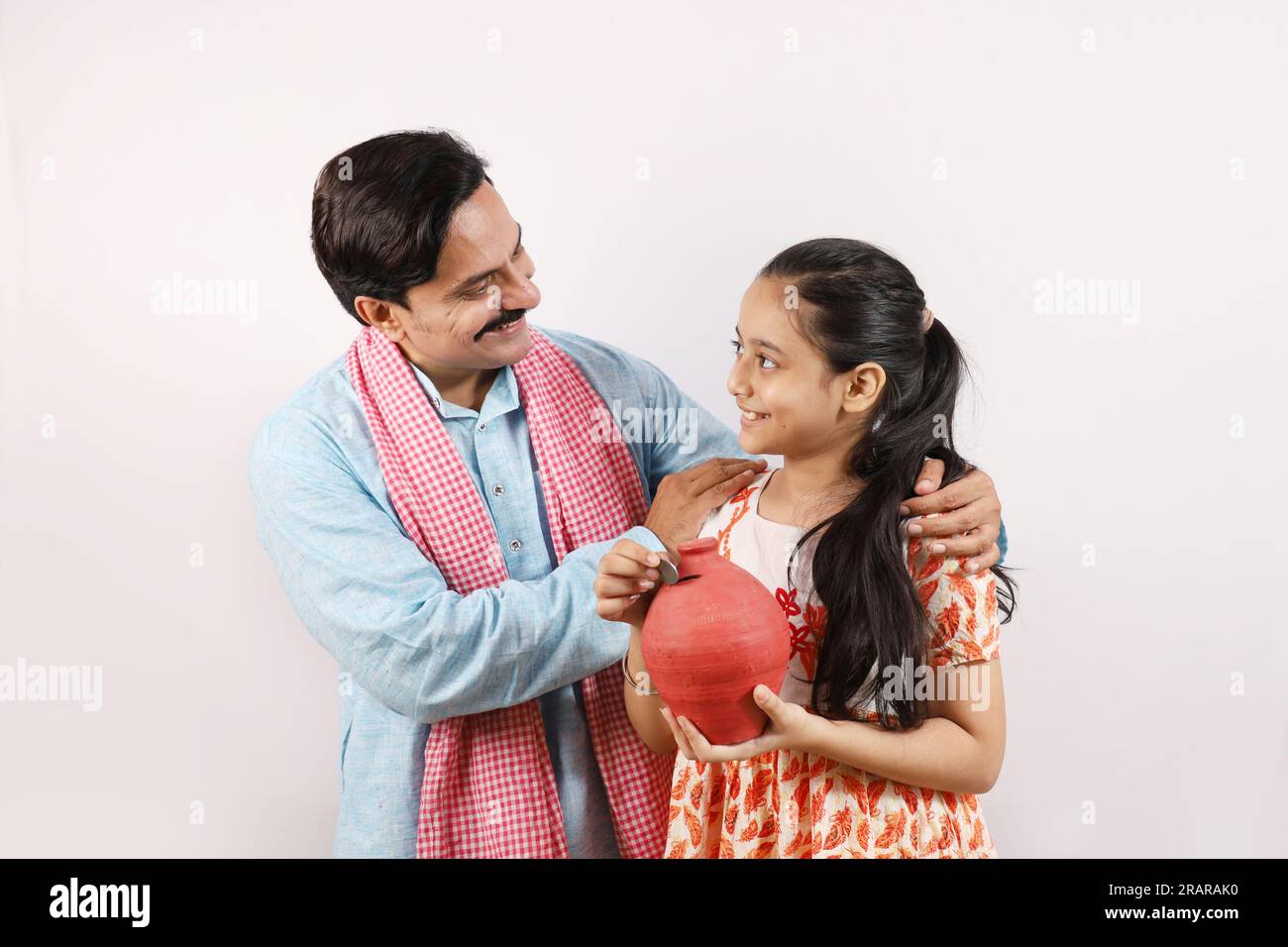 Happy Indian rural father and daughter holding piggy bank in hand ...