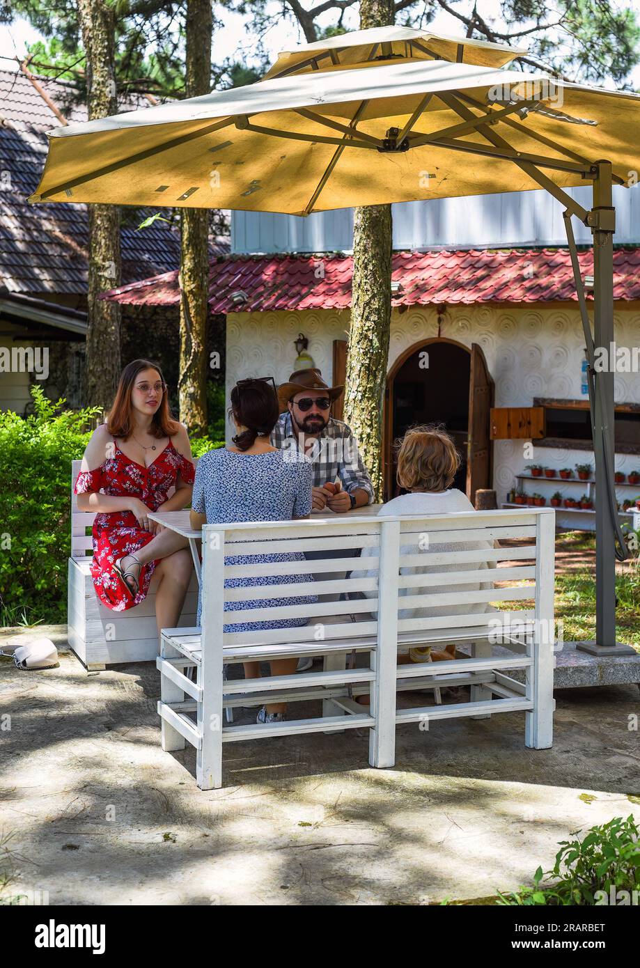 Family members father, mother and two daughters sit in alcove in park ...