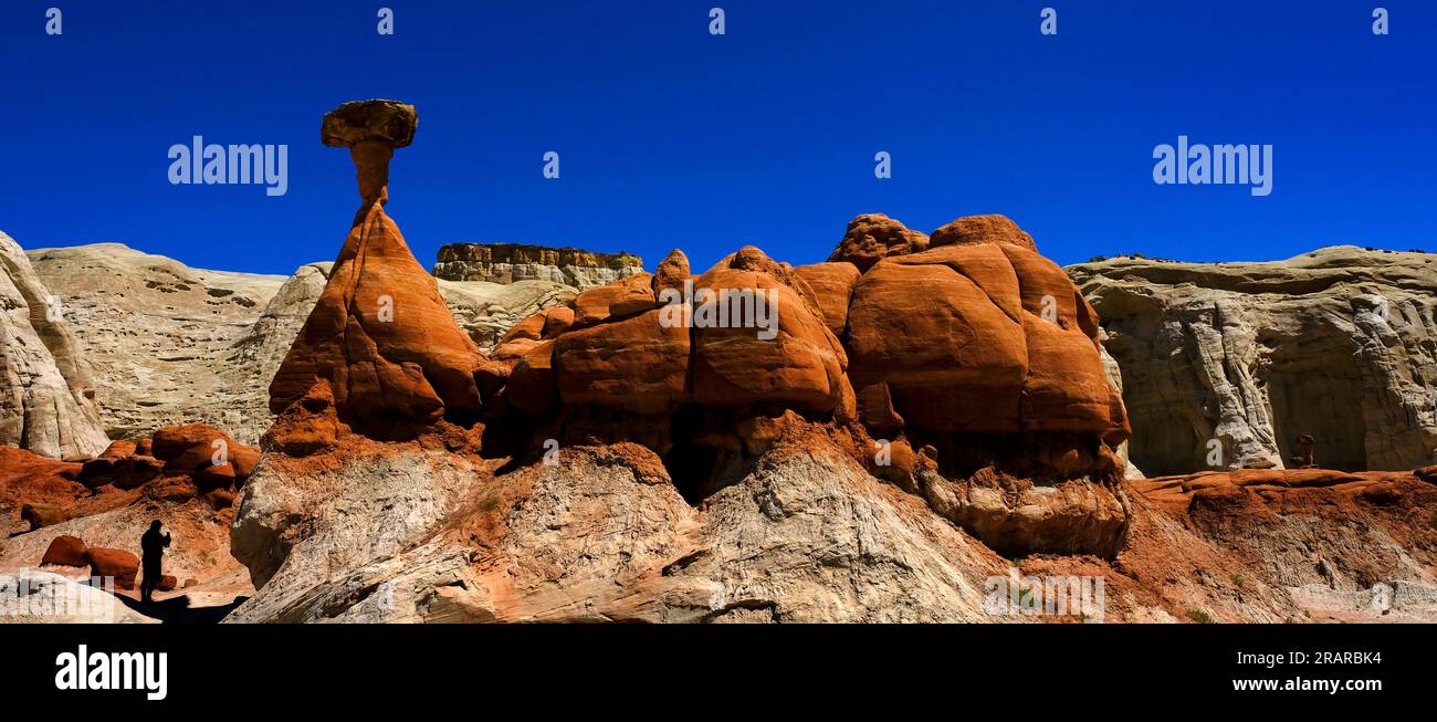 People in silhouette at Toadstool hoodoos in the Southwest with red sandstone and blue sky in wilderness Stock Photo