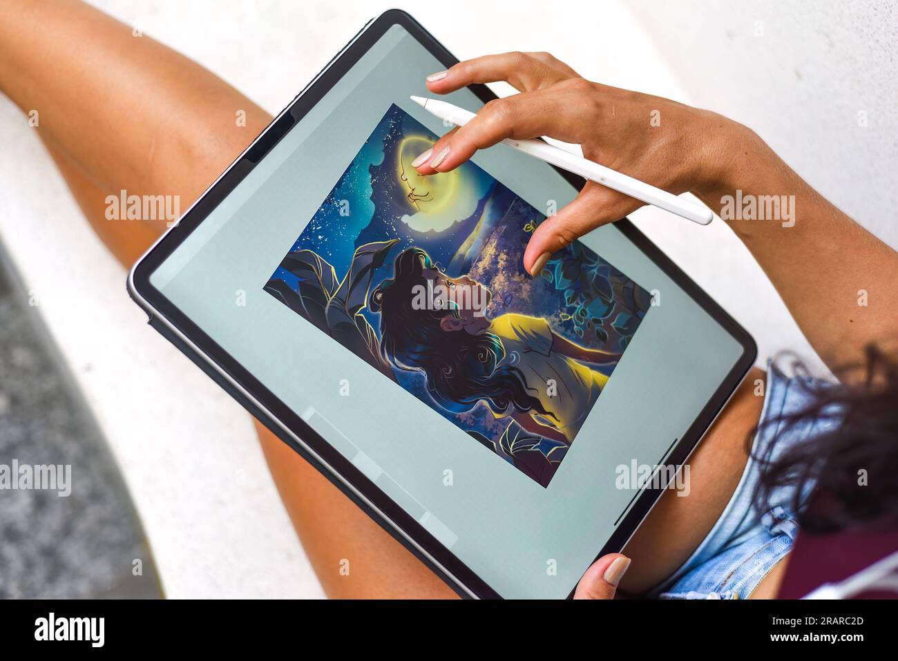 Brunette woman artist and illustration drawing, using electronical tablet and stylus, increasing size of the picture by using touchscreen Stock Photo