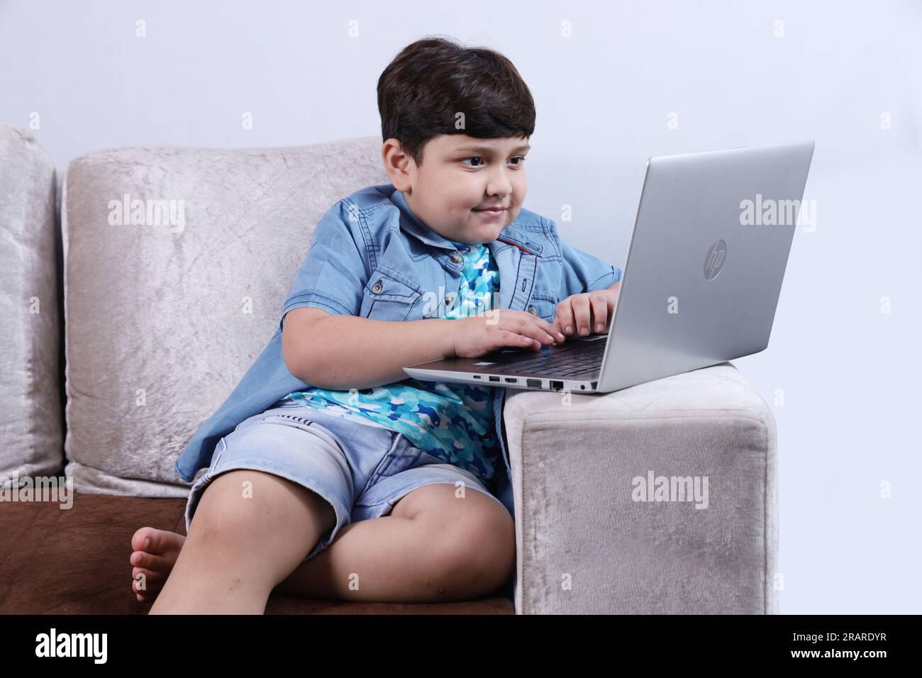 Happy Indian kid surfing laptop having pleasant time together joyfully. the child is surfing on internet and looking into the laptop. Stock Photo