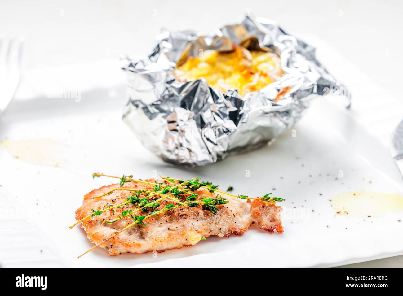 https://c8.alamy.com/comp/2RARERG/poulry-steak-with-baked-potato-in-aluminum-foil-2RARERG.jpg