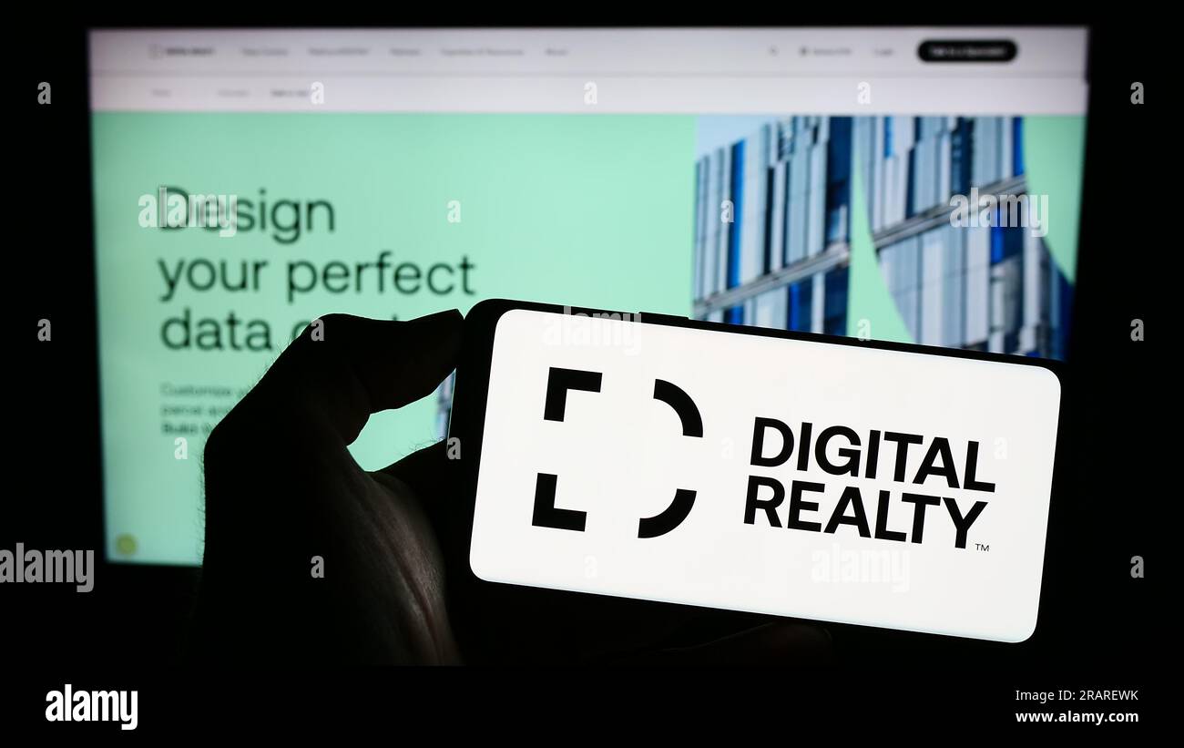 Person holding smartphone with logo of US data center company Digital Realty Trust Inc. on screen in front of website. Focus on phone display. Stock Photo