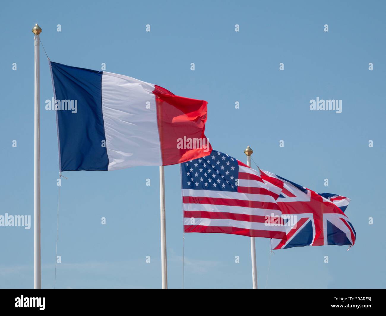 The flags of France, USA and the European Union (EU) waving in the wind on a flagpoles with blue sky background. Stock Photo