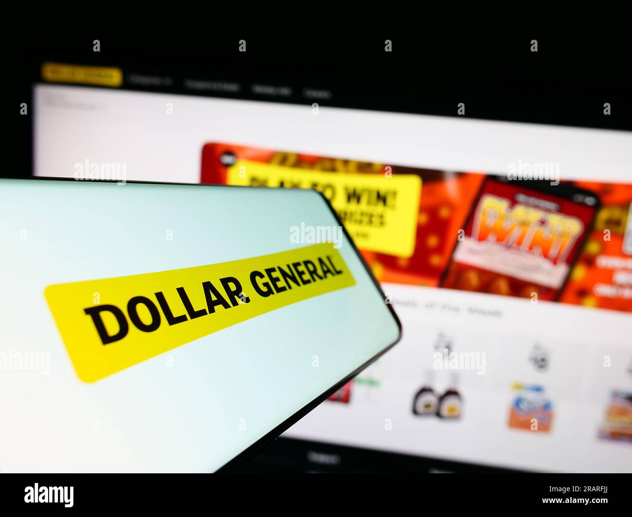 Cellphone with logo of American retail company Dollar General Corporation on screen in front of website. Focus on center-left of phone display. Stock Photo