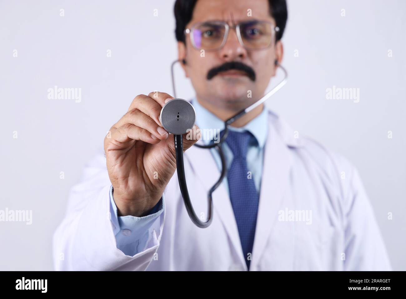 Portrait of happy Indian doctor in uniform showing stethoscope and