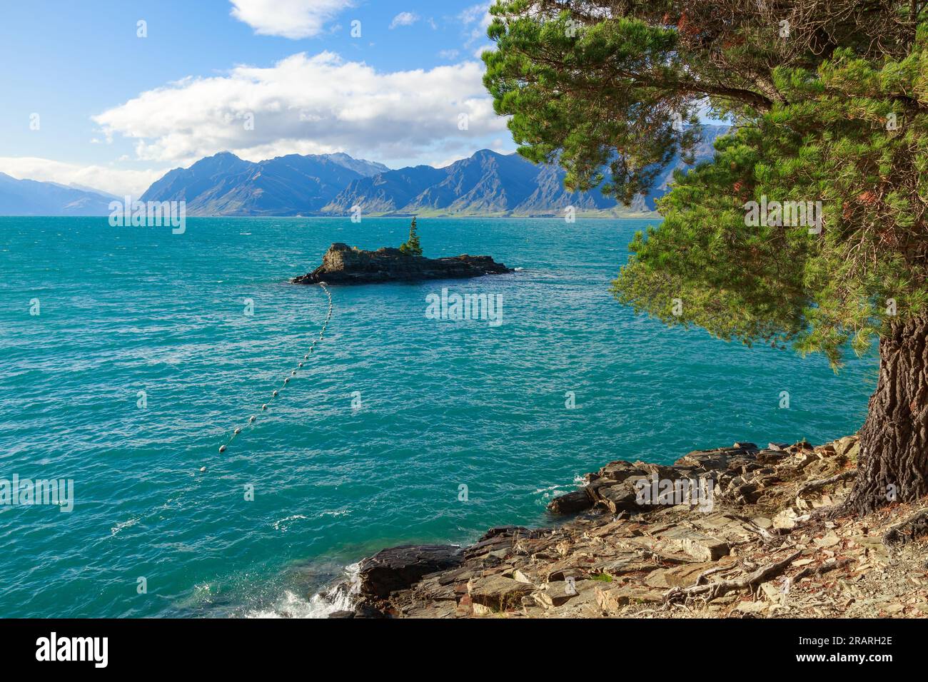 Lake Hawea in the Otago district of New Zealand's South Island. The booms leading to the tiny island protect the lake's dam from logs and debris. Stock Photo