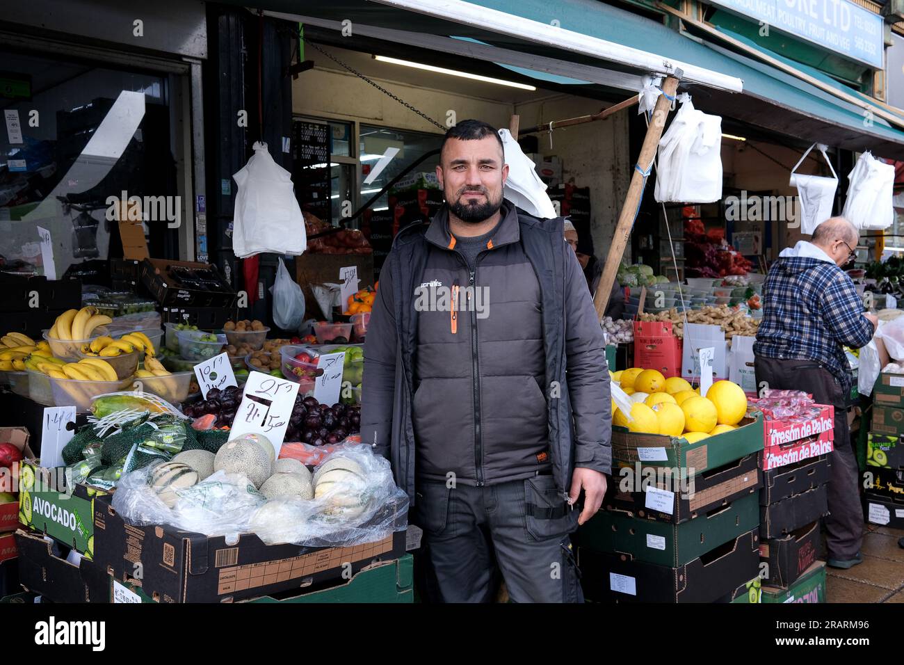 Street market stall holder outside his fresh fruit and vegetable shop