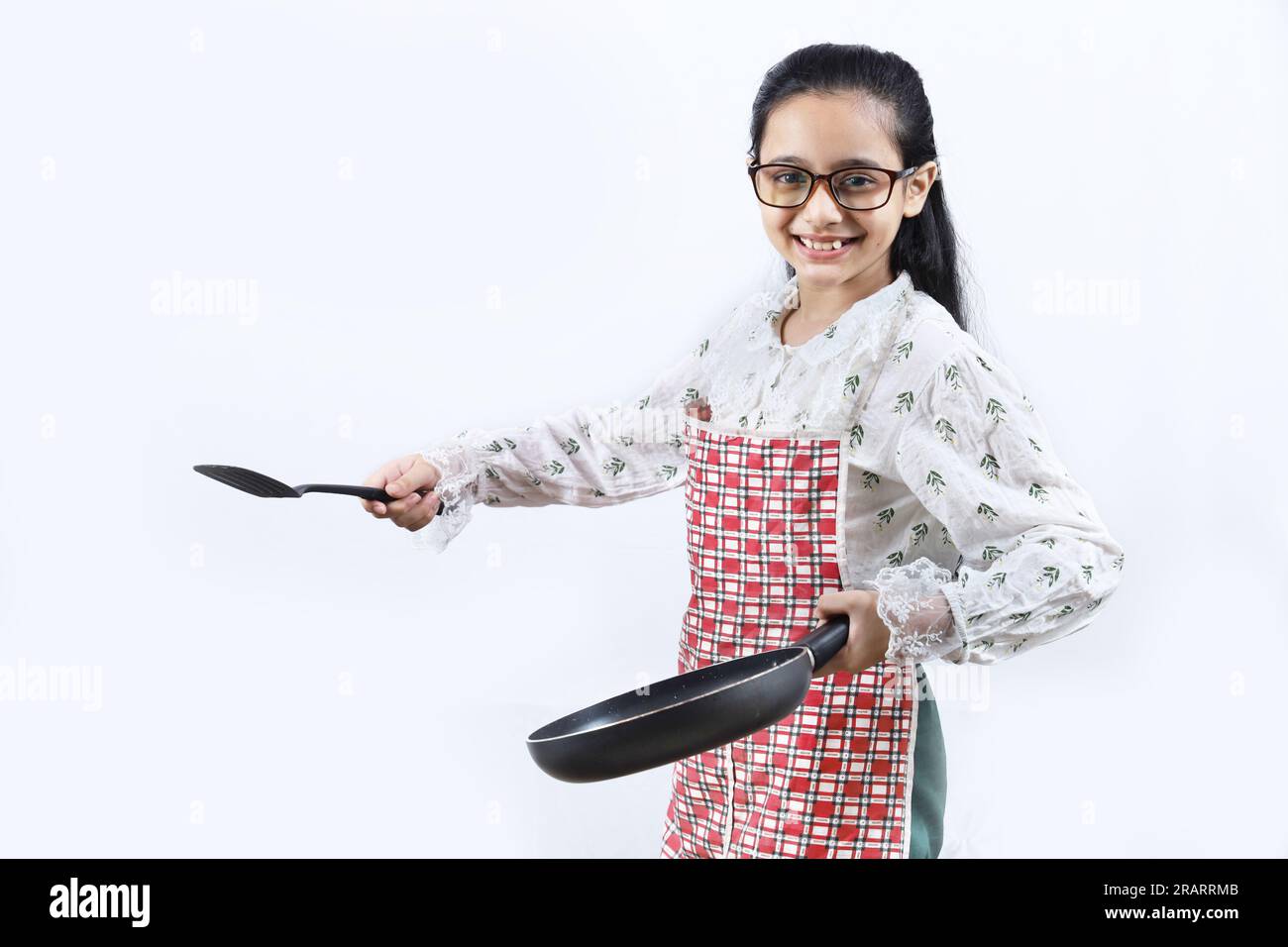 Portrait of Happy Indian teenage girl in kitchen holding cooking accessories. Rolling Rin