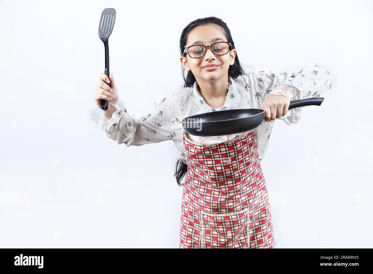 Portrait of Happy Indian teenage girl in kitchen holding cooking accessories. Rolling Rin