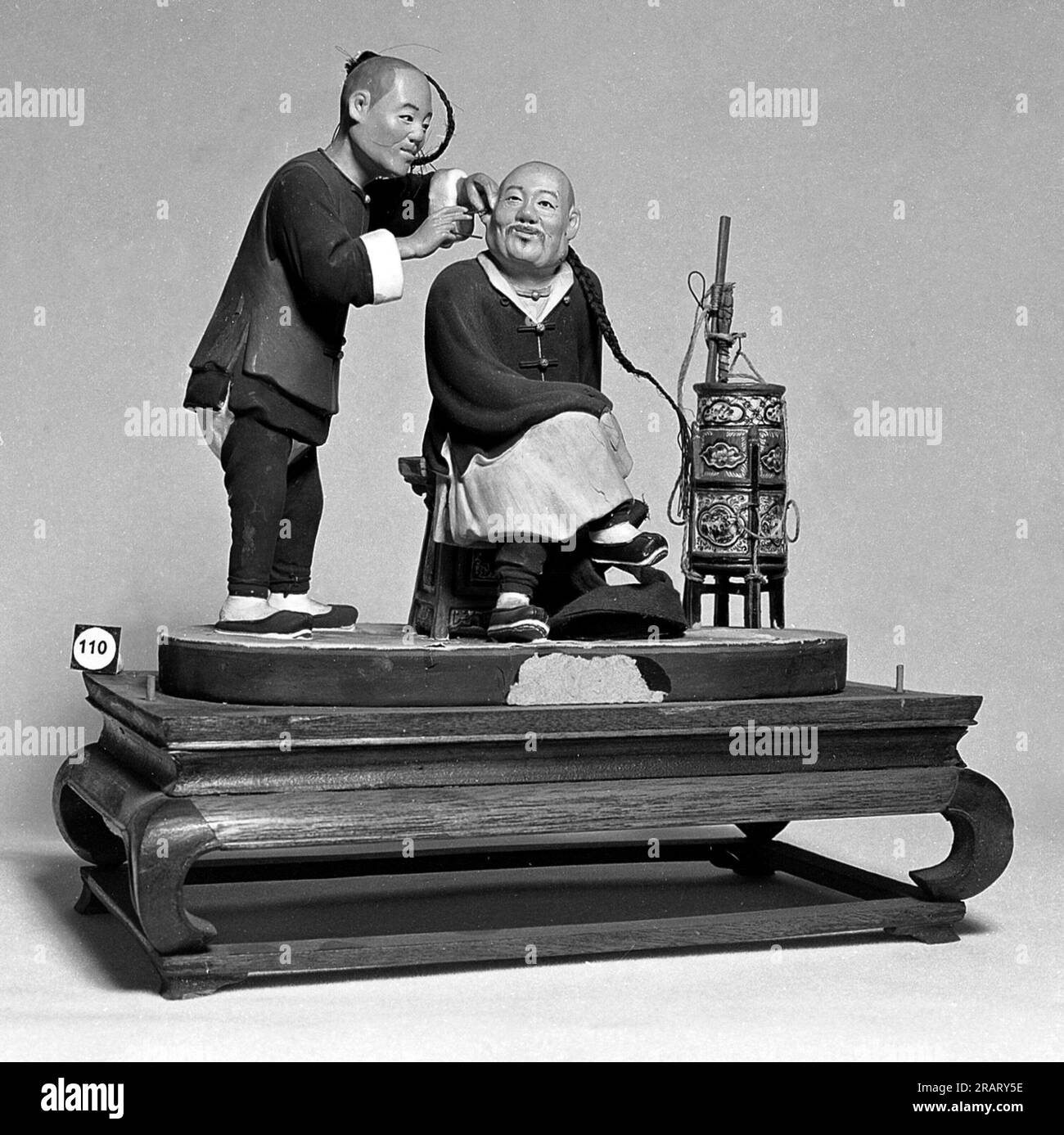 Model of Chinese barber cleaning ears of client. - Description Group of