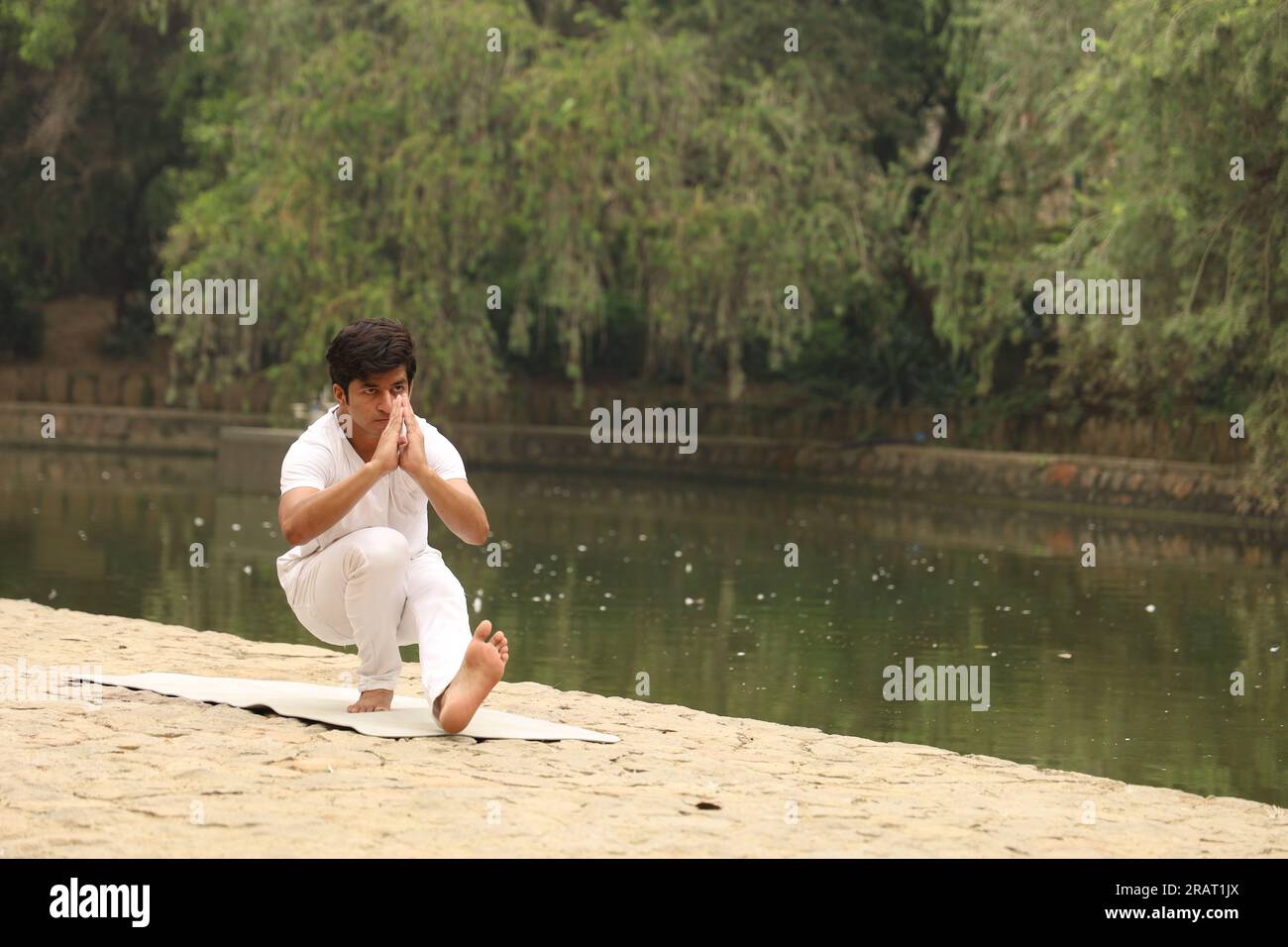 Young boy exercising and doing Yoga poses in green serene environment early morning in park to maintain healthy lifestyle. International yoga day. Stock Photo