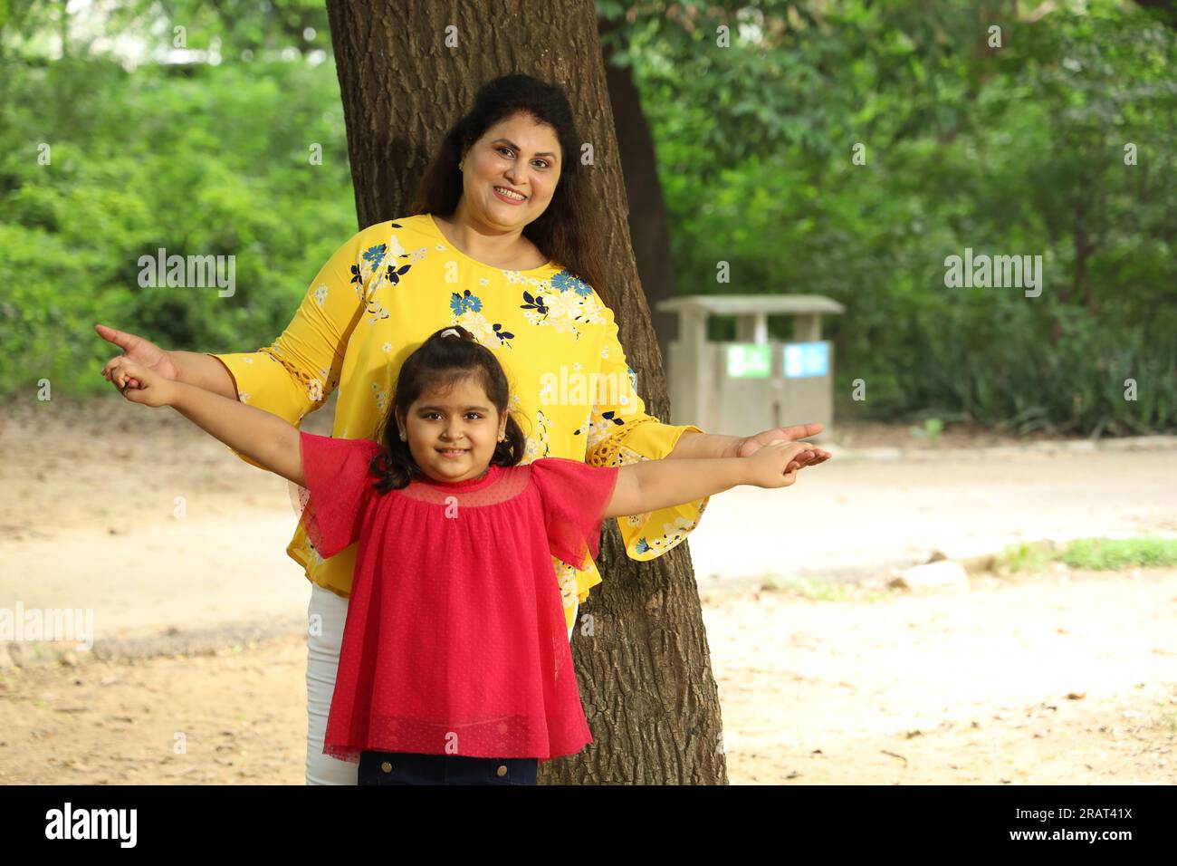 Happy mother and daughter enjoying their time together in a public park. single mother playing with her daughter in green and clean atmosphere. Stock Photo