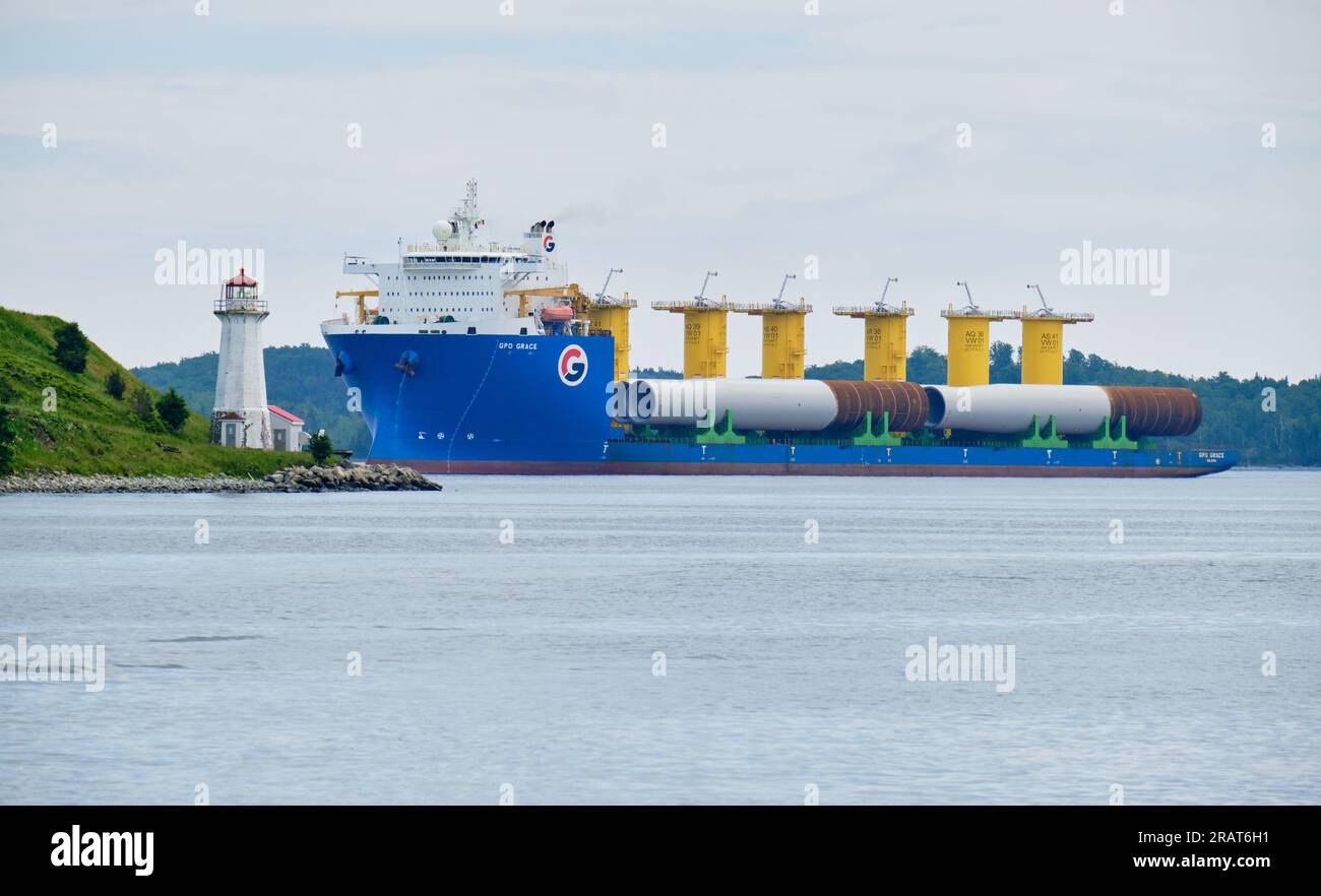Halifax, Nova Scotia, Canada. July 5th, 2023. The GPO Grace, a Heavylift vessel, loaded with wind turbine monopiles destined for the USA's first utility-scale offshore wind energy project off the coast of Massachusetts enters the Port of Halifax where the project has set up part of its staging area. The ship is seen here passing the George Island lighthouse. Stock Photo