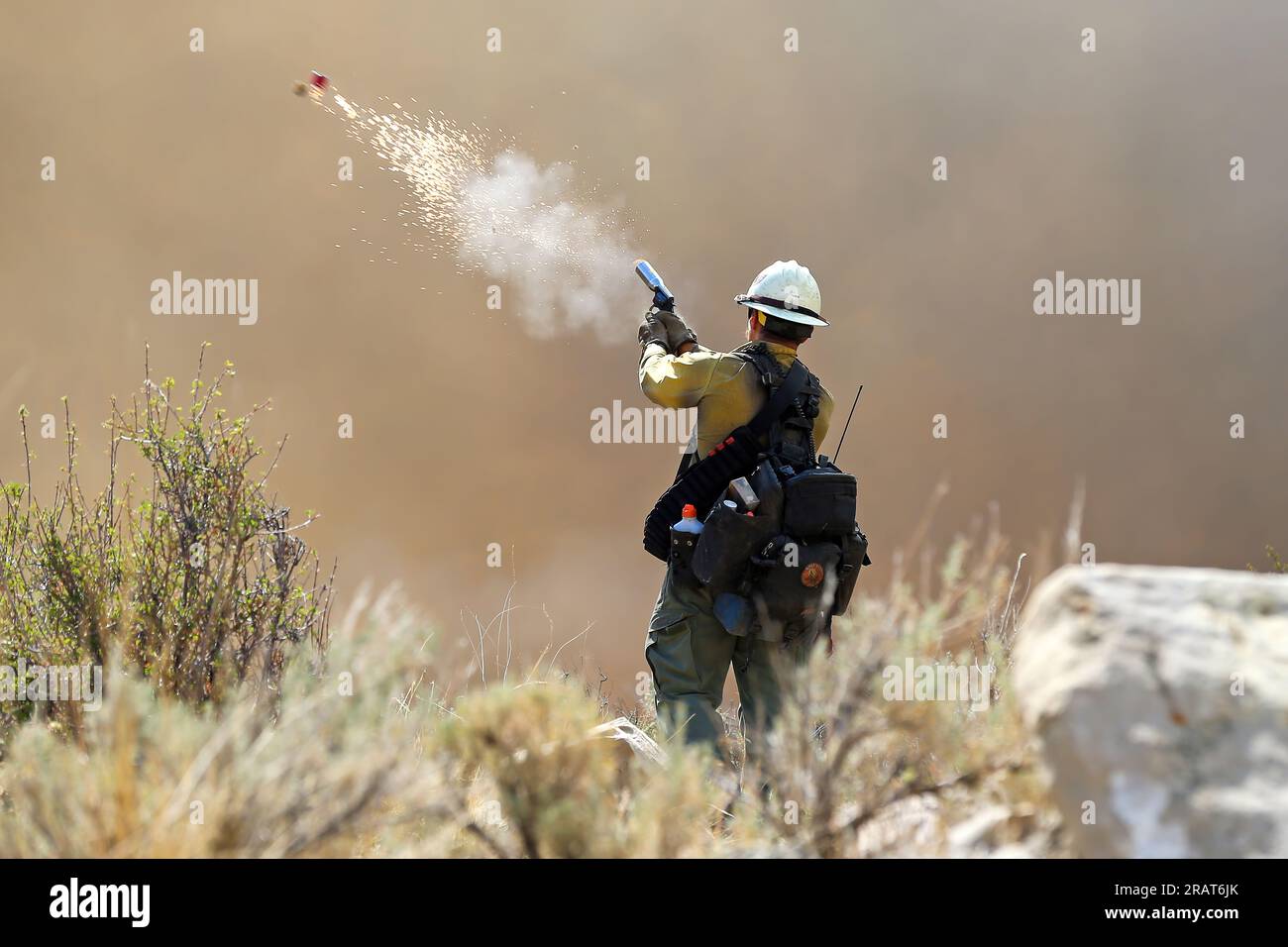 A firefighter with the Wolf Creek Hotshots uses a pistol-style flare launcher during a firing operation on the Bear Fire near Helper, Utah, on June 11, 2021. Stock Photo