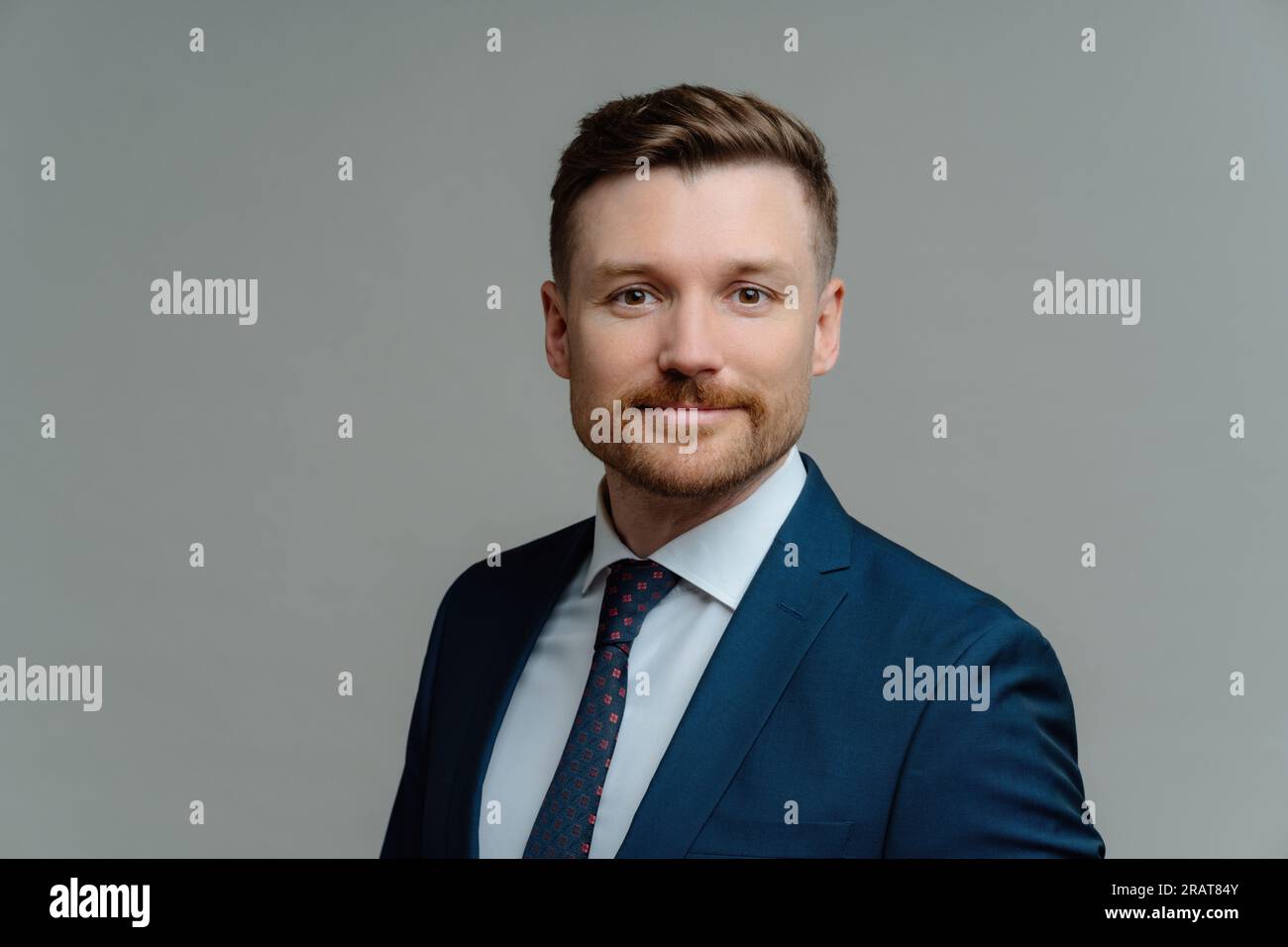 Serious bearded male manager in formal attire poses against grey