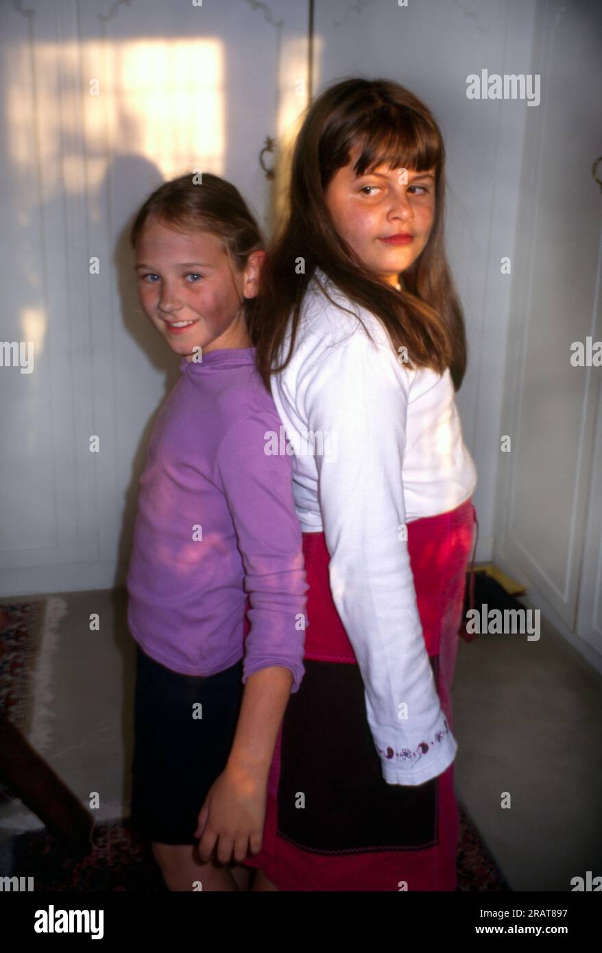 Two nine year old girls standing back to back to show height difference