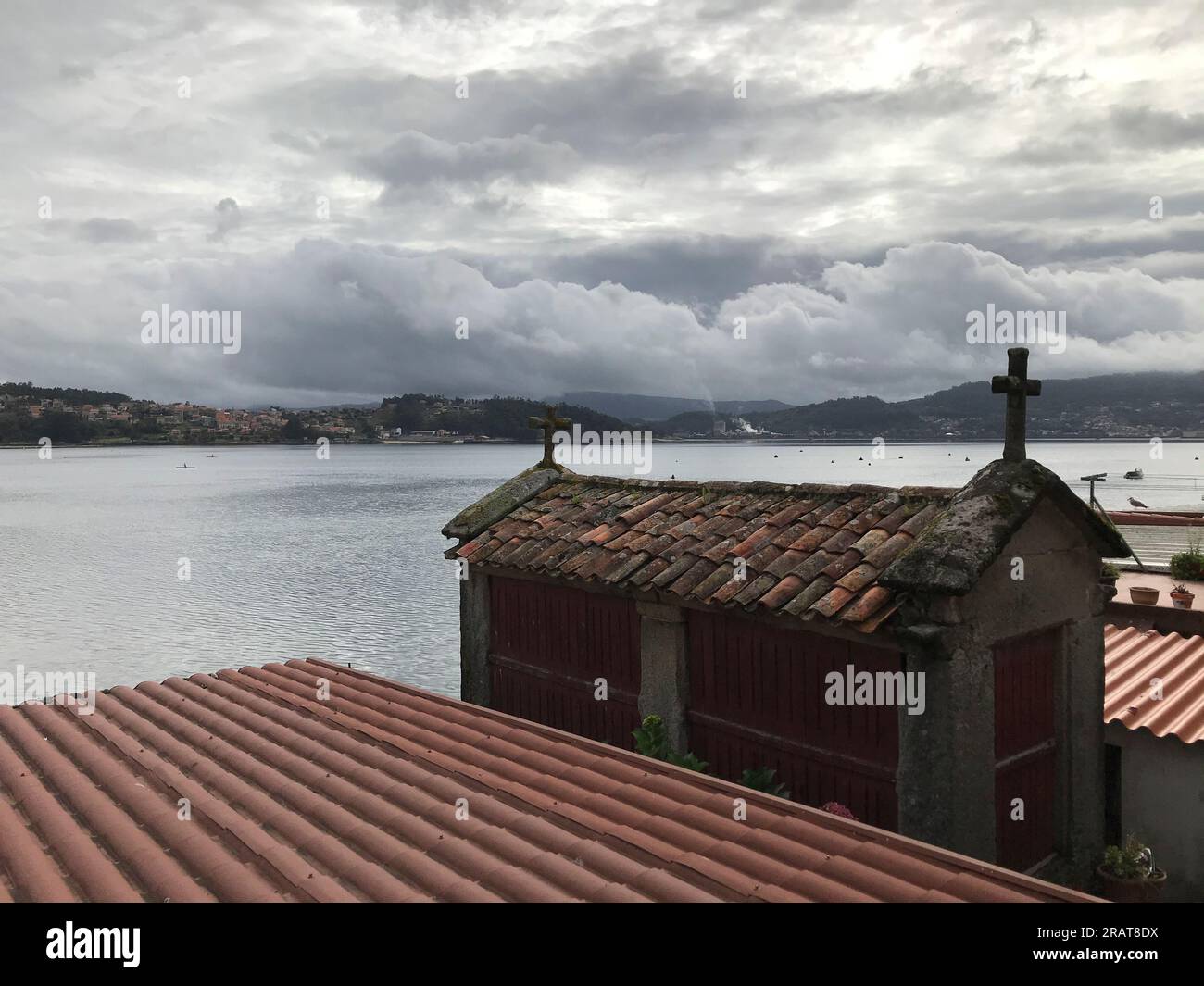 View of an old building used to store cereals and lined with wood with the Galician coast in the background. Stock Photo