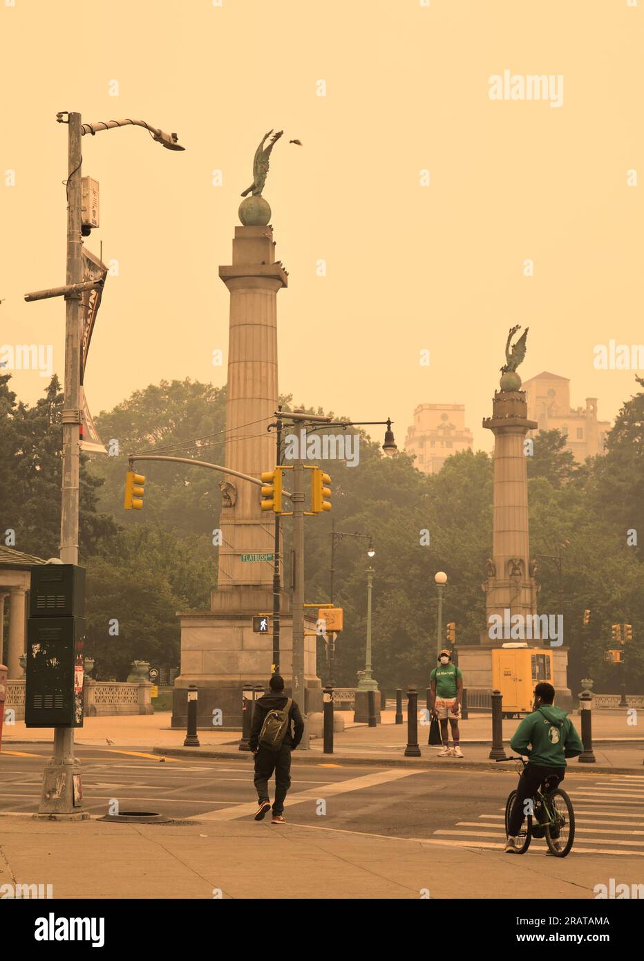 Brooklyn, NY - June 7 2023: People pass by Grand Army Plaza during haze and smoke conditions caused by wildfires in Canada.  Many people are wearing m Stock Photo