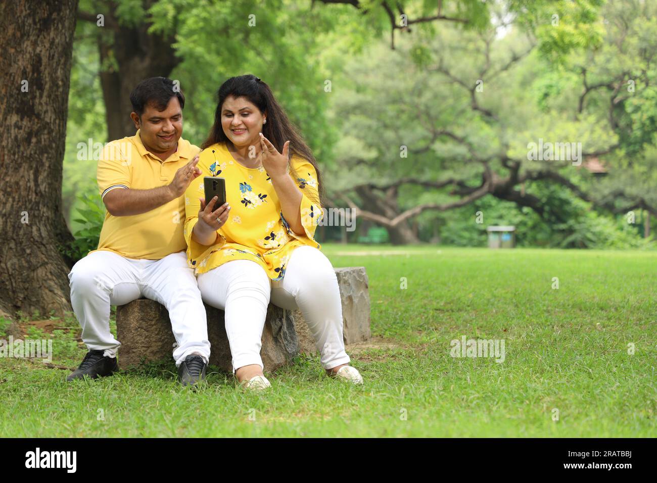 Happy fasto Indian couple taking selfie in a lush green atmosphere. serene and tranquil environment around. Stock Photo