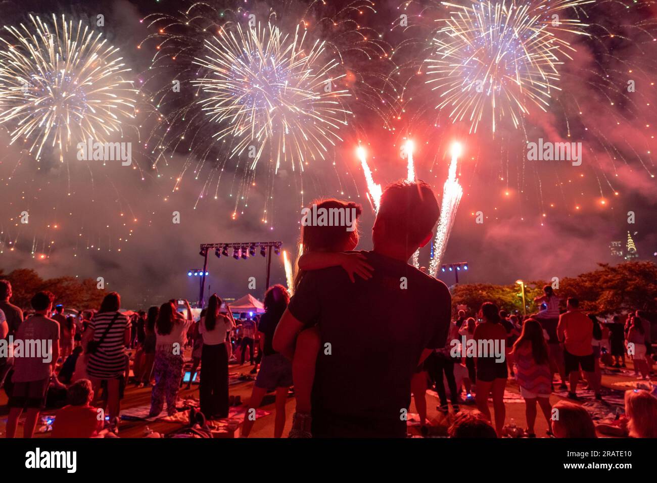 New York, New York, USA. 5th July, 2023. Spectators watch from Gantry State Plaza Park in Long Island as fireworks explode over the east river during the annual Macy's 4th of July Fireworks display as New York city celebrates Independence Day, over the Empire State Building and the Manhattan skyline. (Credit Image: © TheNEWS2 via ZUMA Press Wire) EDITORIAL USAGE ONLY! Not for Commercial USAGE! Stock Photo