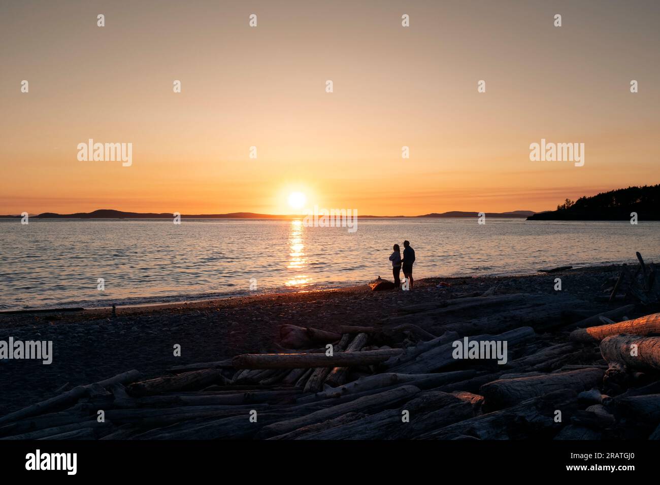 WA24512-00....WASHINGTON - Two people watching the sun set at West Beach in Deception Pass State Park. Stock Photo