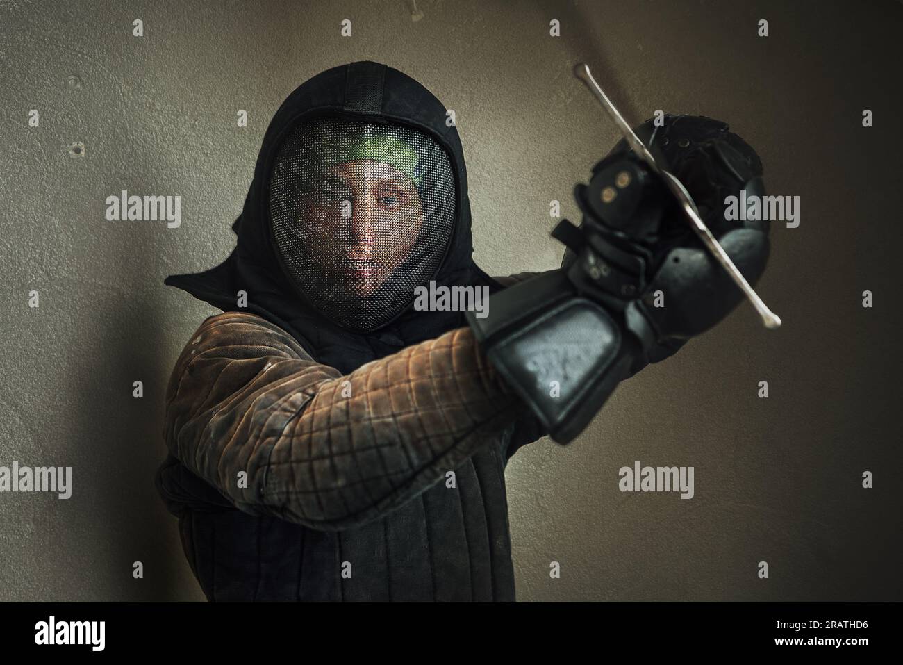 Portrait of a man dressed in black historical fencing armor and fencing